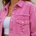 Close-up of pink distressed denim shacket showing flap pocket, buttons, and frayed detailing
