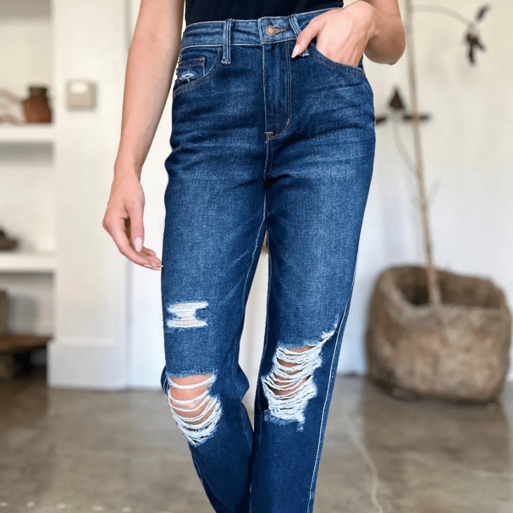 Close-up of heavy distressing on dark wash straight-leg jeans.