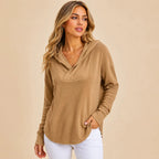 Women's camel drop shoulder waffle knit hoodie featuring a crossover hood, relaxed fit and long sleeves styled with white jeans in a boutique setting.