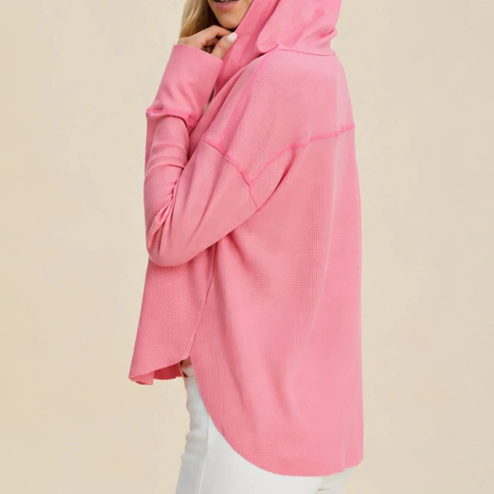 Side profile of the women's pink waffle knit hoodie showing the relaxed drop shoulder design, crossover hood and curved hem.