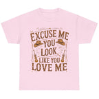 Light pink graphic t-shirt featuring the "Excuse Me You Look Like You Love Me" western-inspired graphic with cowboy hats and guitars.