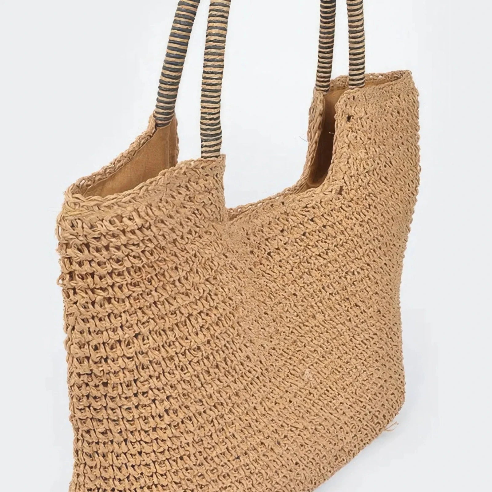 Angled view of a khaki faux straw tote bag with woven texture, spacious design, and striped shoulder handles.