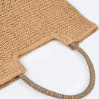 Close-up of the striped shoulder handles and woven texture on a khaki faux straw tote bag.