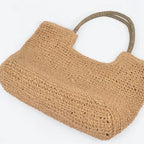 Bottom view of a khaki faux straw tote bag highlighting woven construction and roomy everyday design.