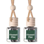 Two small clear glass reed diffuser bottles with beige wooden caps and hanging cords, each labeled 'Flannel Pine' on a dark green front label, shown on a white background.
