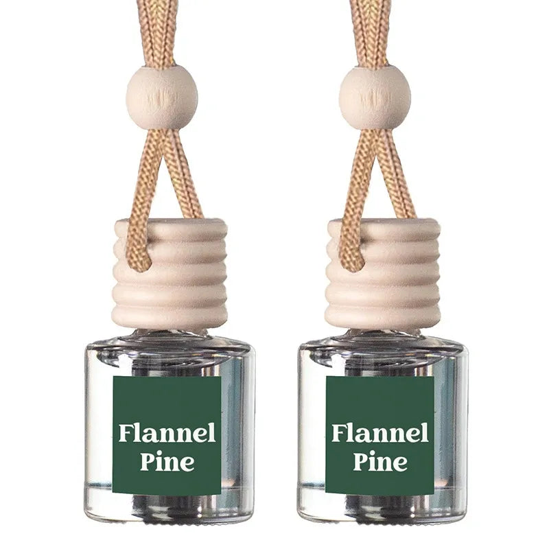 Two small clear glass reed diffuser bottles with beige wooden caps and hanging cords, each labeled 'Flannel Pine' on a dark green front label, shown on a white background.