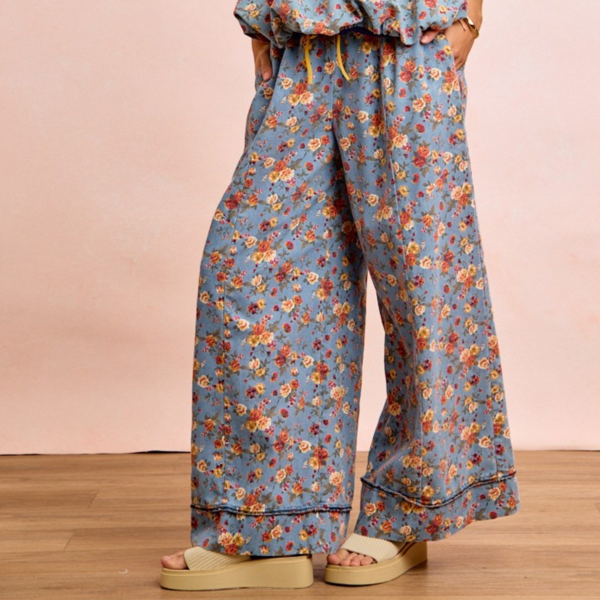 Person wearing floral pants with a pink background