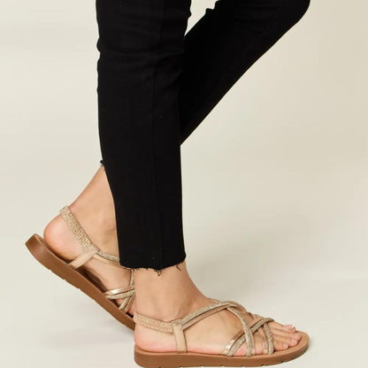 Full-length view of the Forever Link rhinestone crisscross sandals highlighting the metallic gold finish.