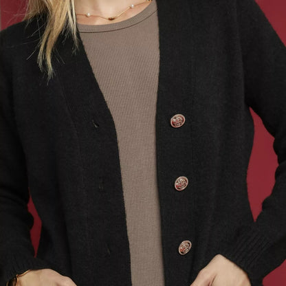Person wearing a black cardigan with button details on a red background