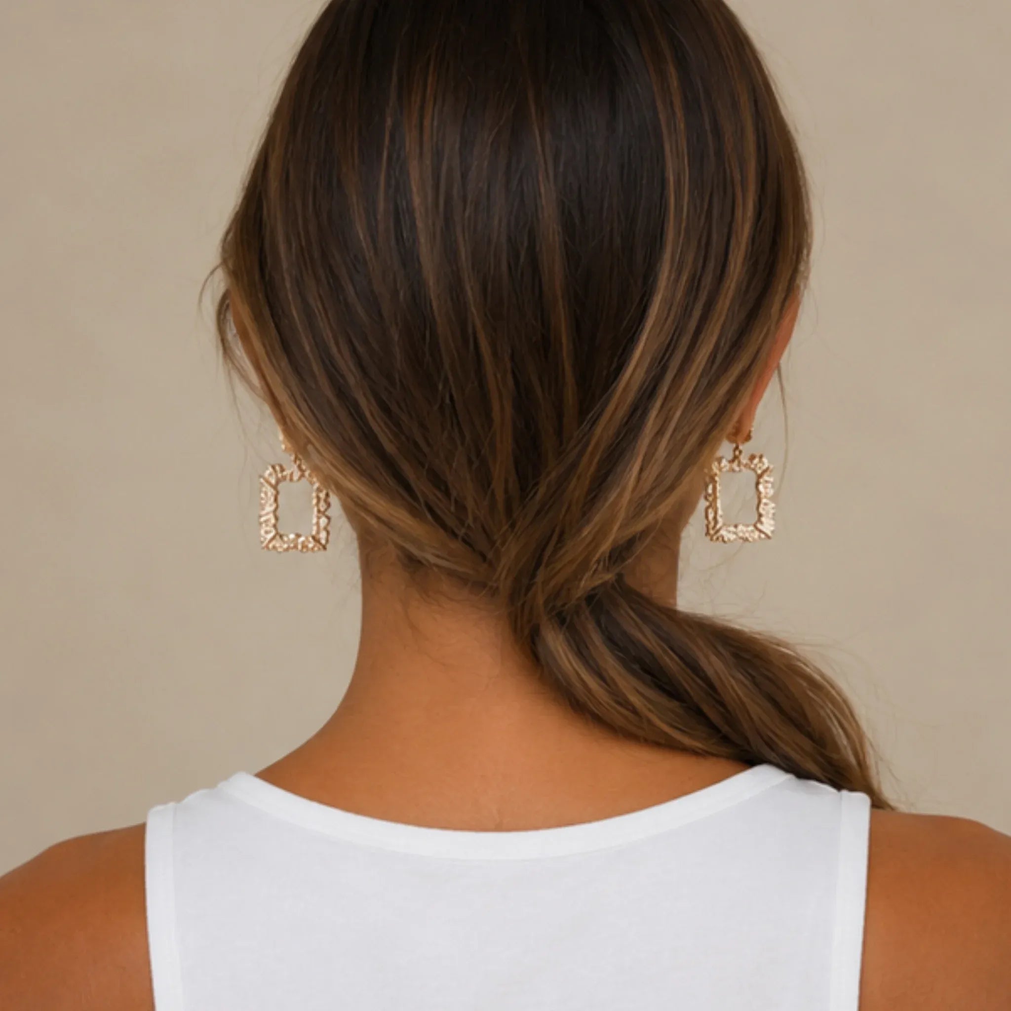 Back view of woman wearing gold rhinestone dangle earrings highlighting the elegant drop length.
