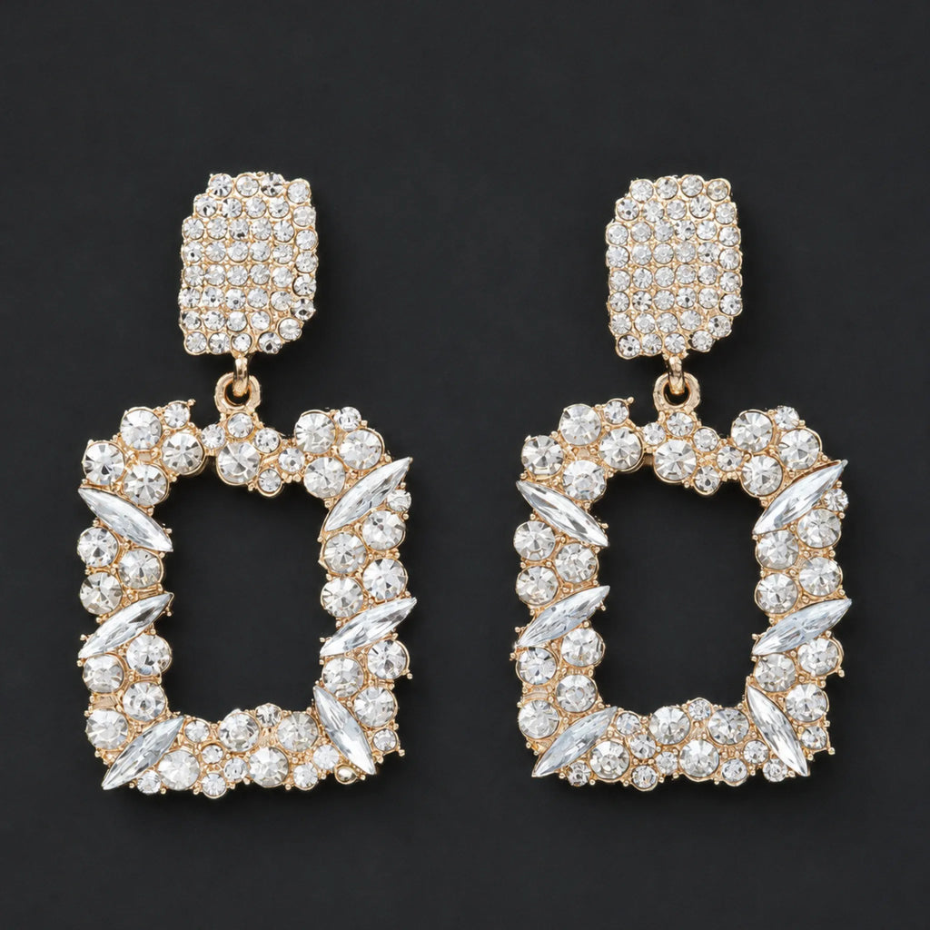 Gold rhinestone dangle earrings with sparkling crystal accents displayed in a flat lay on a black background.