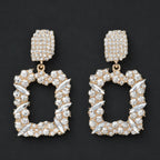 Gold rhinestone dangle earrings with sparkling crystal accents displayed in a flat lay on a black background.