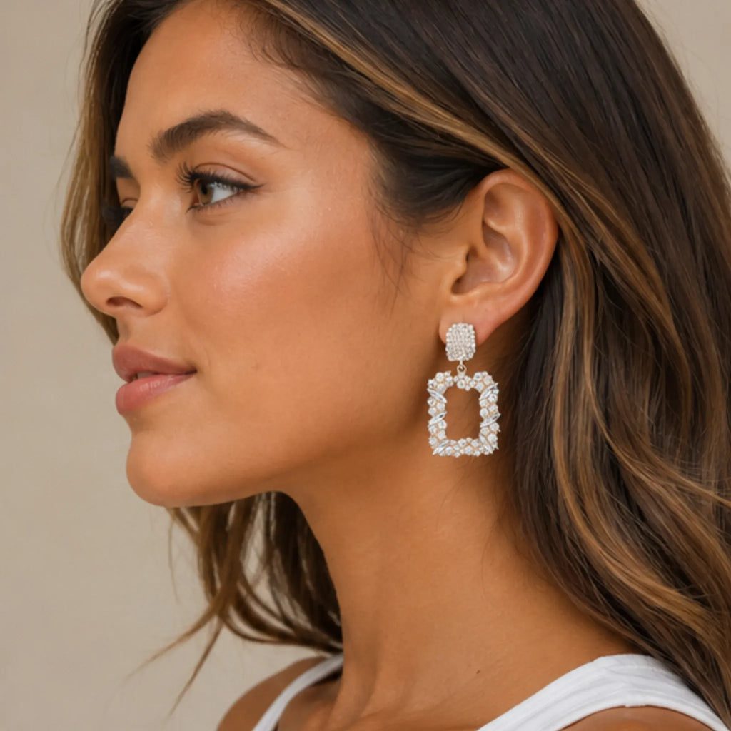 Side profile of woman wearing gold rhinestone dangle earrings with elegant geometric rhinestone design.