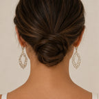 Back view of woman wearing gold rhinestone drop earrings with an elegant low bun hairstyle.