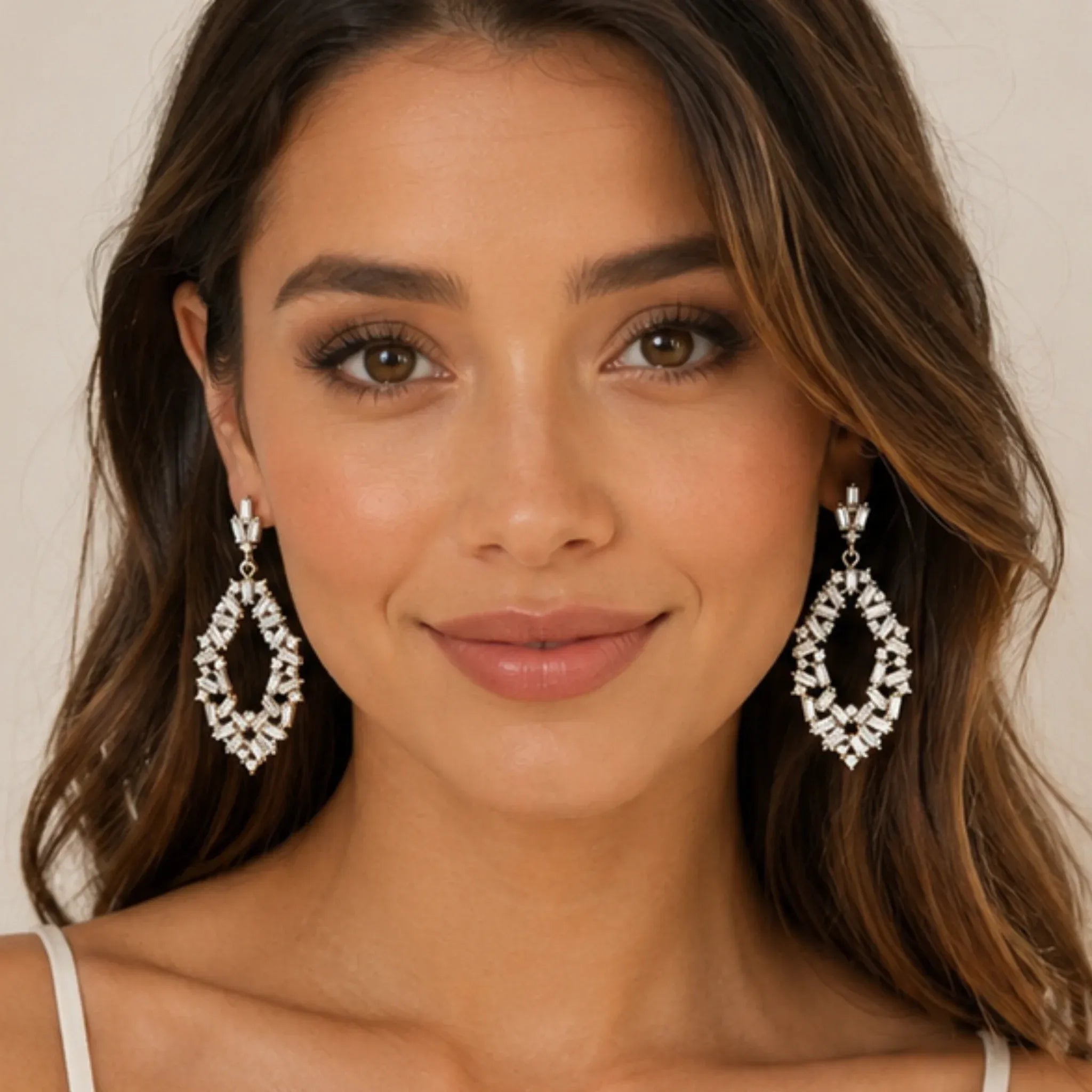 Woman wearing gold rhinestone drop earrings with sparkling baguette-cut crystals, front view.