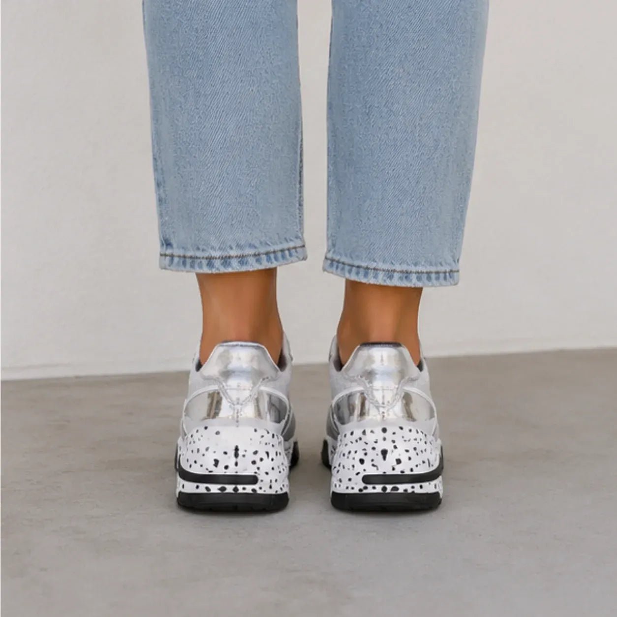 Rear view of women's gray platform sneakers with metallic heel detail and speckled wedge outsole.