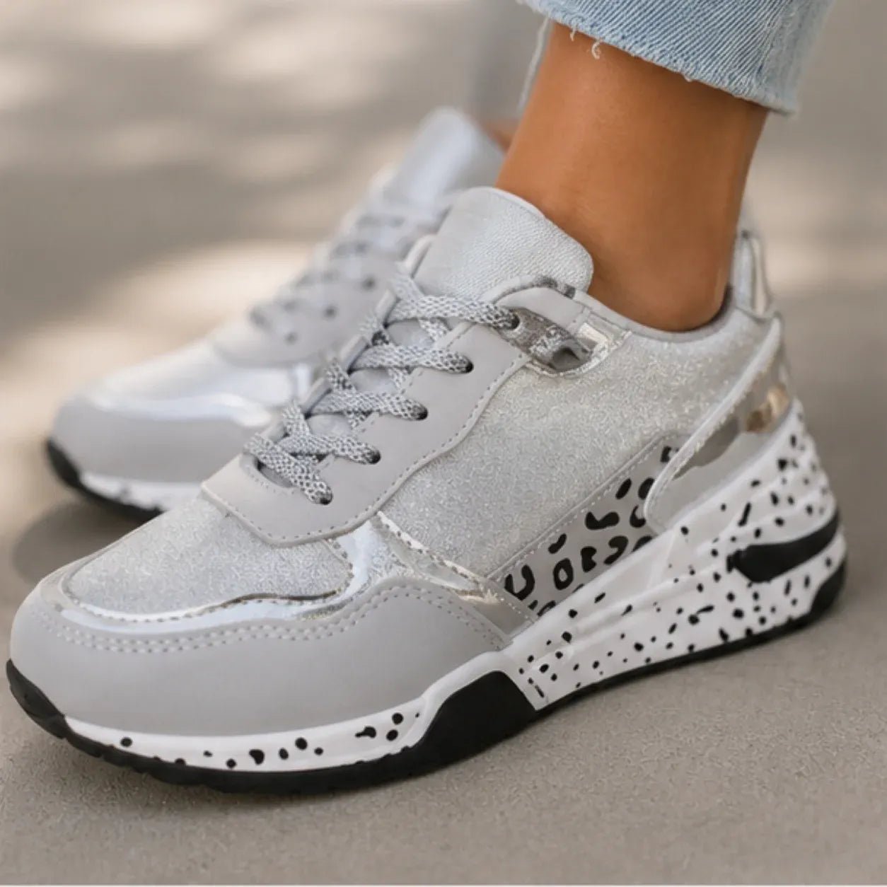 Close-up of women's gray lace-up platform sneakers featuring suede upper, metallic accents, and speckled rubber wedge sole.