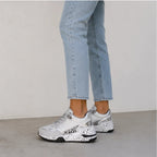 Side view of women's gray lace-up platform sneakers featuring metallic panels, color-block design, and cushioned wedge sole.