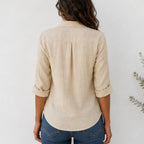 Back view of women's beige linen blend long sleeve collared blouse with relaxed fit and curved hem.