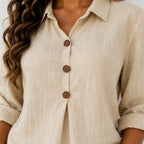 Close-up of women's beige linen blend blouse featuring wooden buttons, collared neckline, and textured fabric.