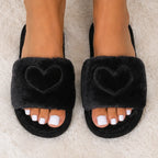 Close-up of black Heart Plush House Slippers featuring a plush faux fur upper with embroidered heart detail.