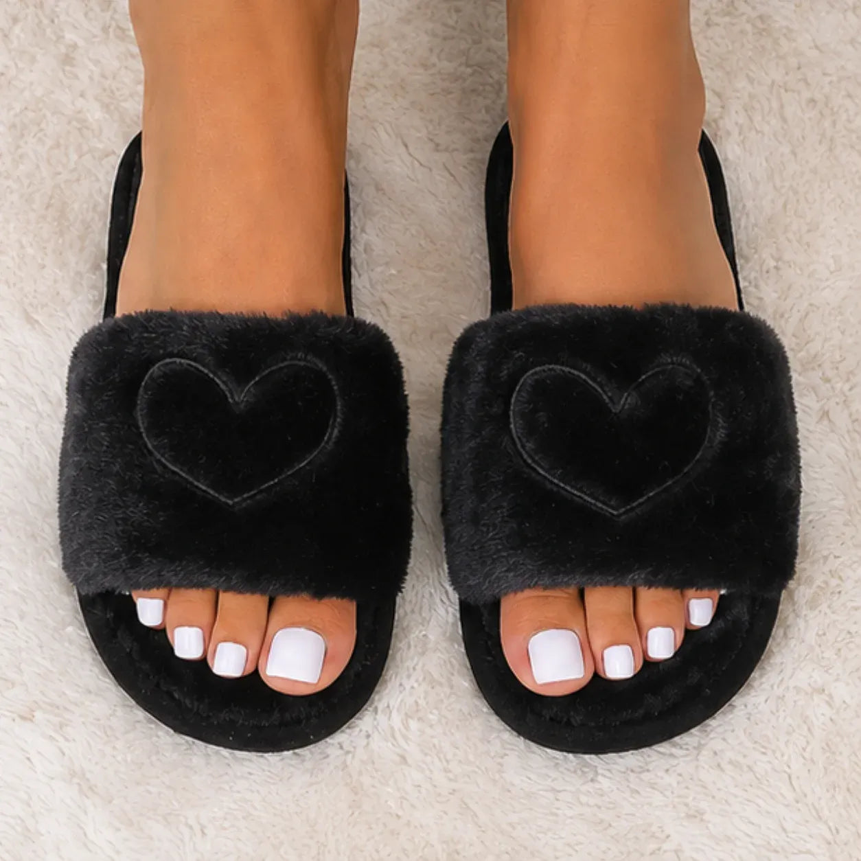 Close-up of black Heart Plush House Slippers featuring a plush faux fur upper with embroidered heart detail.