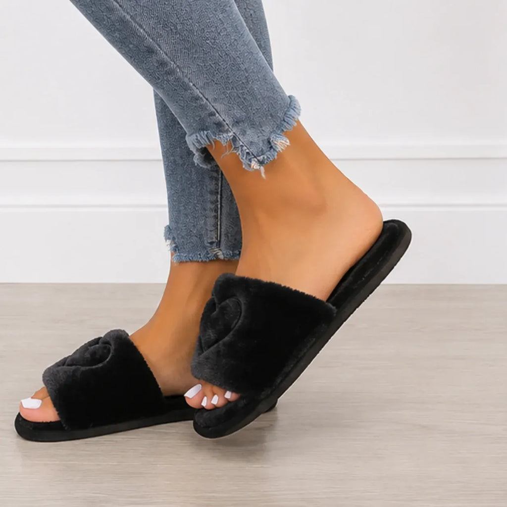 Side profile of black Heart Plush House Slippers showing soft faux fur construction and cushioned sole.