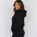 Side view of women's black hooded fleece-lined zip-up sweatshirt showing hood and relaxed fit