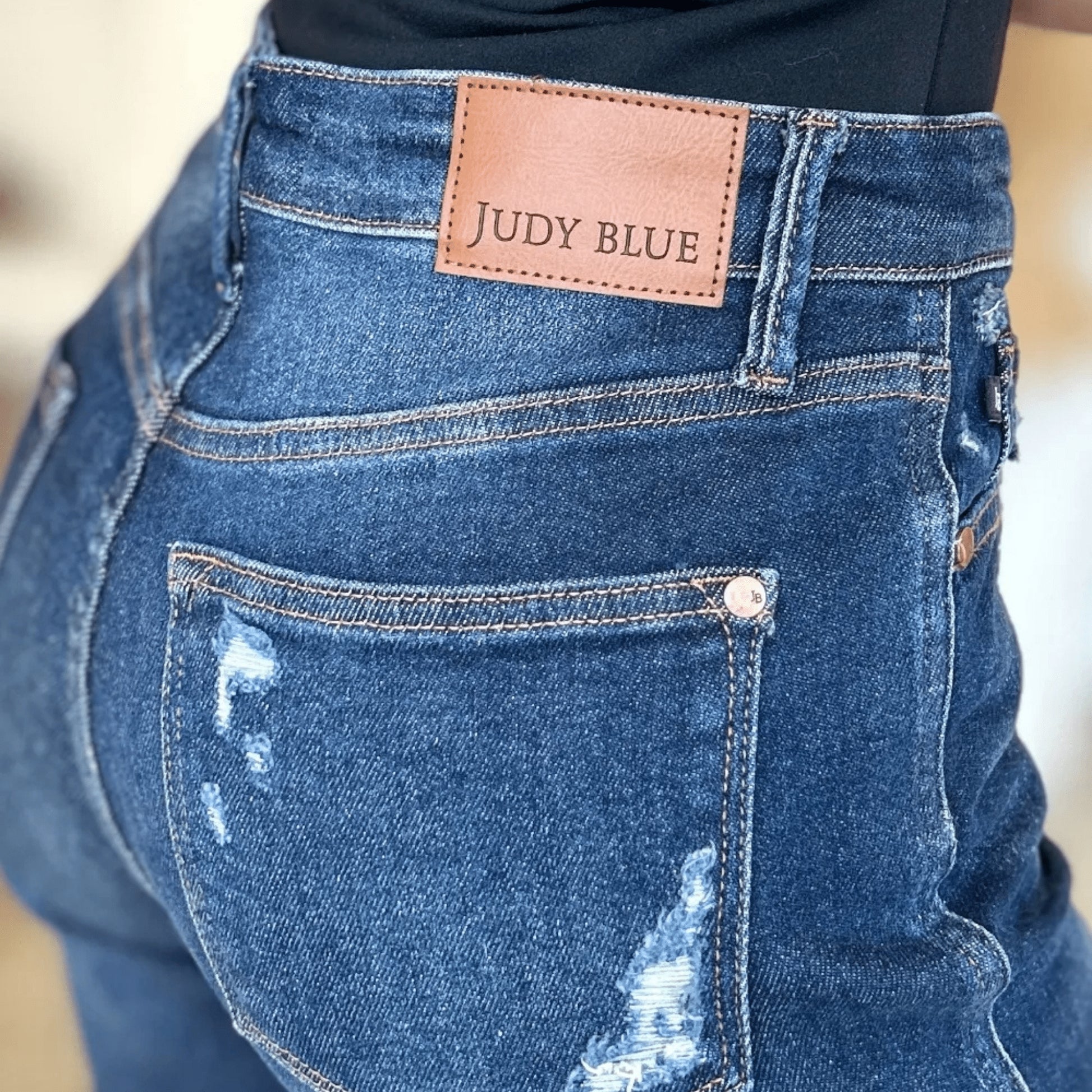 Close-up of the Judy Blue brand label on the back pocket of dark wash jeans.