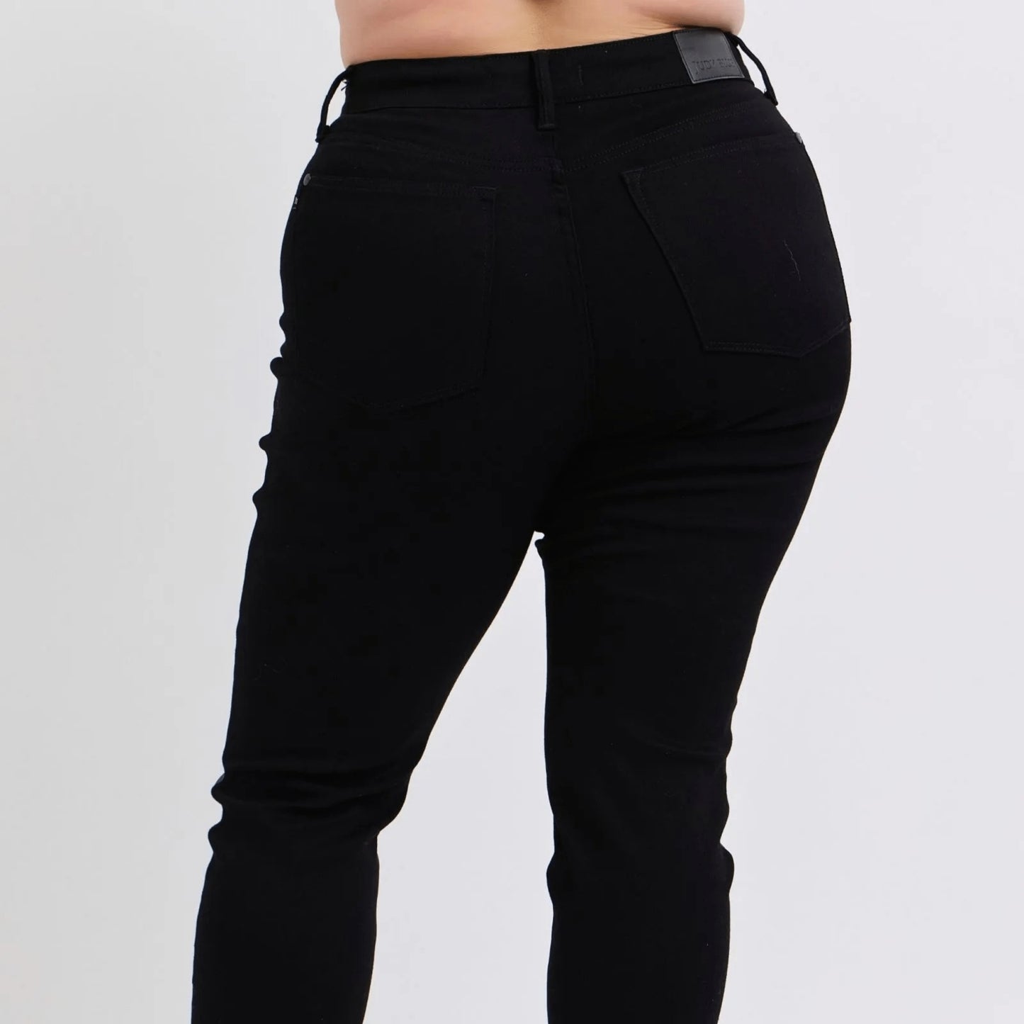 Side profile of plus size faux leather skinny pants showing the smooth, contoured silhouette.