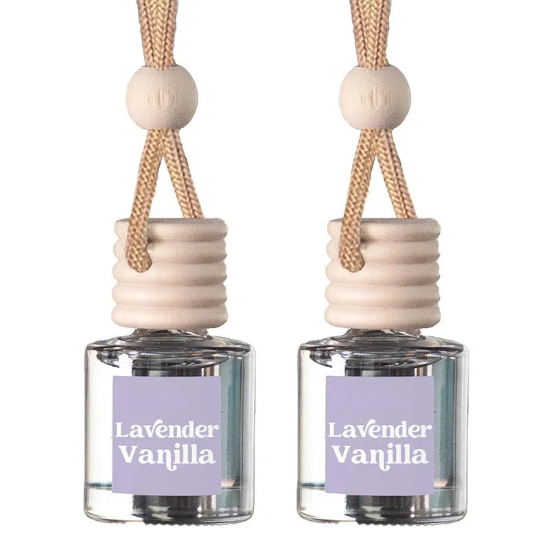 Two lavender vanilla reed diffusers with clear glass bottles, light wood caps, and beige hanging cords on a white background.