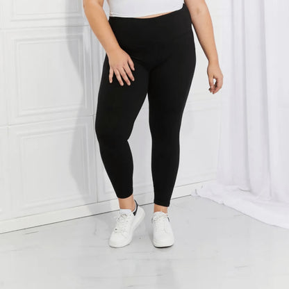 Complete presentation of black performance leggings with white sneakers on a white background.