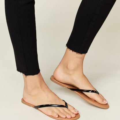 Person wearing black sandals with thin straps on a neutral background