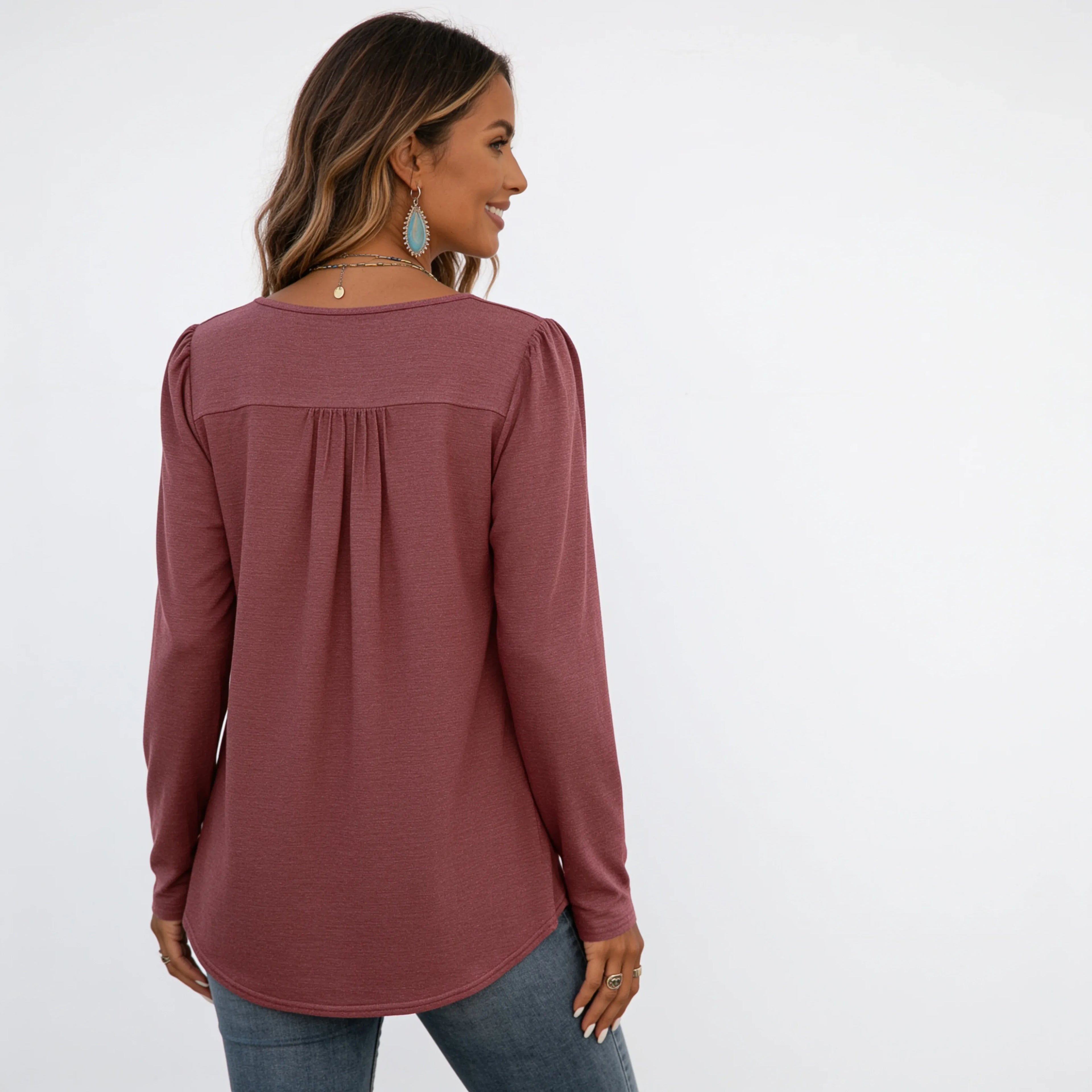 Back view of the women's brick red long sleeve crew neck essential top featuring a relaxed fit, gathered back yoke, and curved hemline.