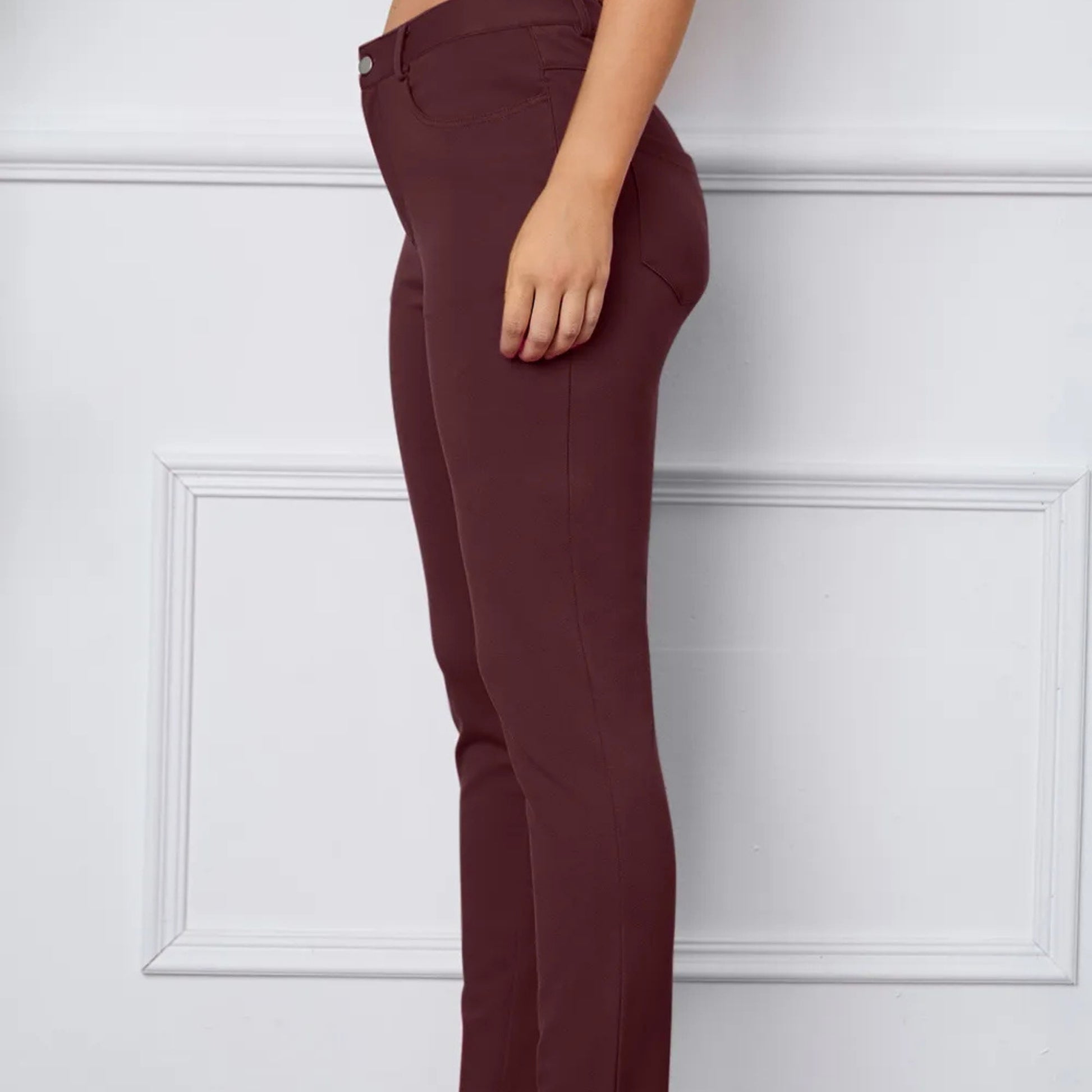 Maroon pants worn by a person against a white paneled wall