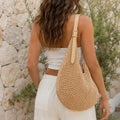 Back view of a women's natural mesh crochet shoulder bag featuring an adjustable faux leather shoulder strap and roomy woven design.
