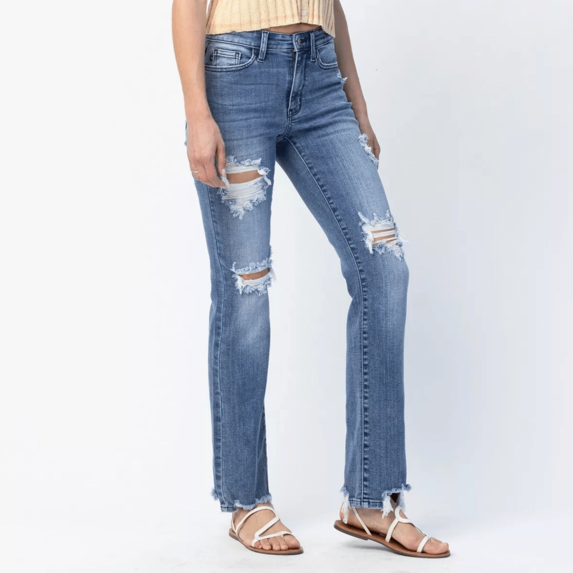 Detailed view of the mid-rise waist and distressing on straight leg jeans.