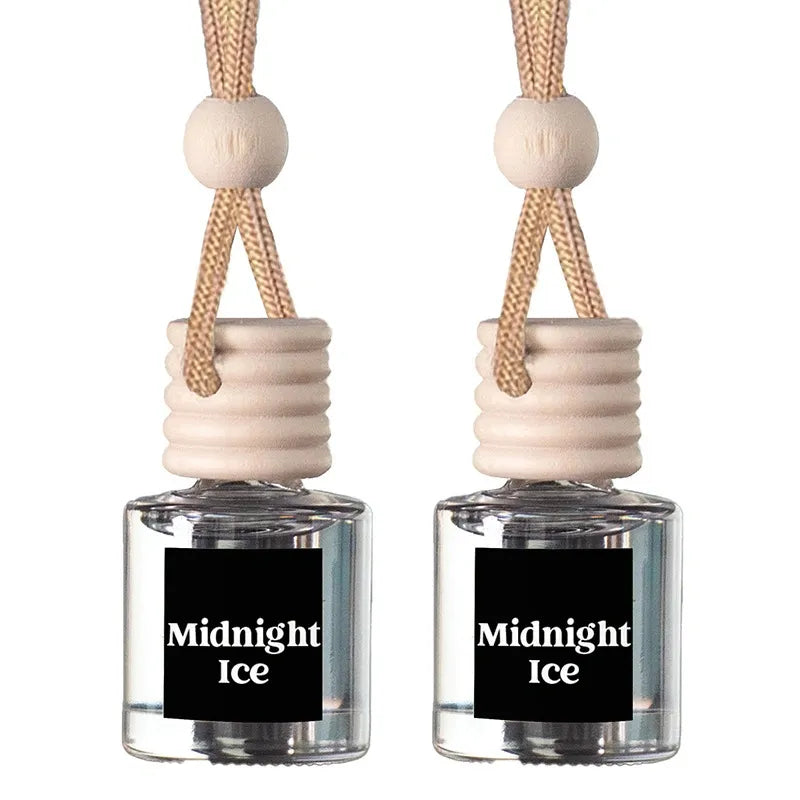 Two small reed diffuser bottles with clear glass bodies, beige wooden stoppers, and cream hanging cords, each labeled 'Midnight Ice' on a black front label, shown on a white background.