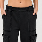 Close-up of black mineral wash wide leg cargo pants with a relaxed fit, elastic waistband, and oversized cargo pocket details.