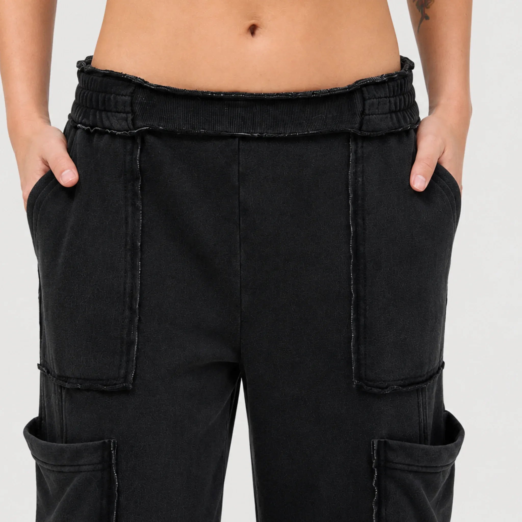 Close-up of black mineral wash wide leg cargo pants with a relaxed fit, elastic waistband, and oversized cargo pocket details.