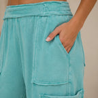 Close-up of turquoise mineral wash wide leg cargo pants highlighting the soft fabric, elastic waistband, and cargo pocket detail.