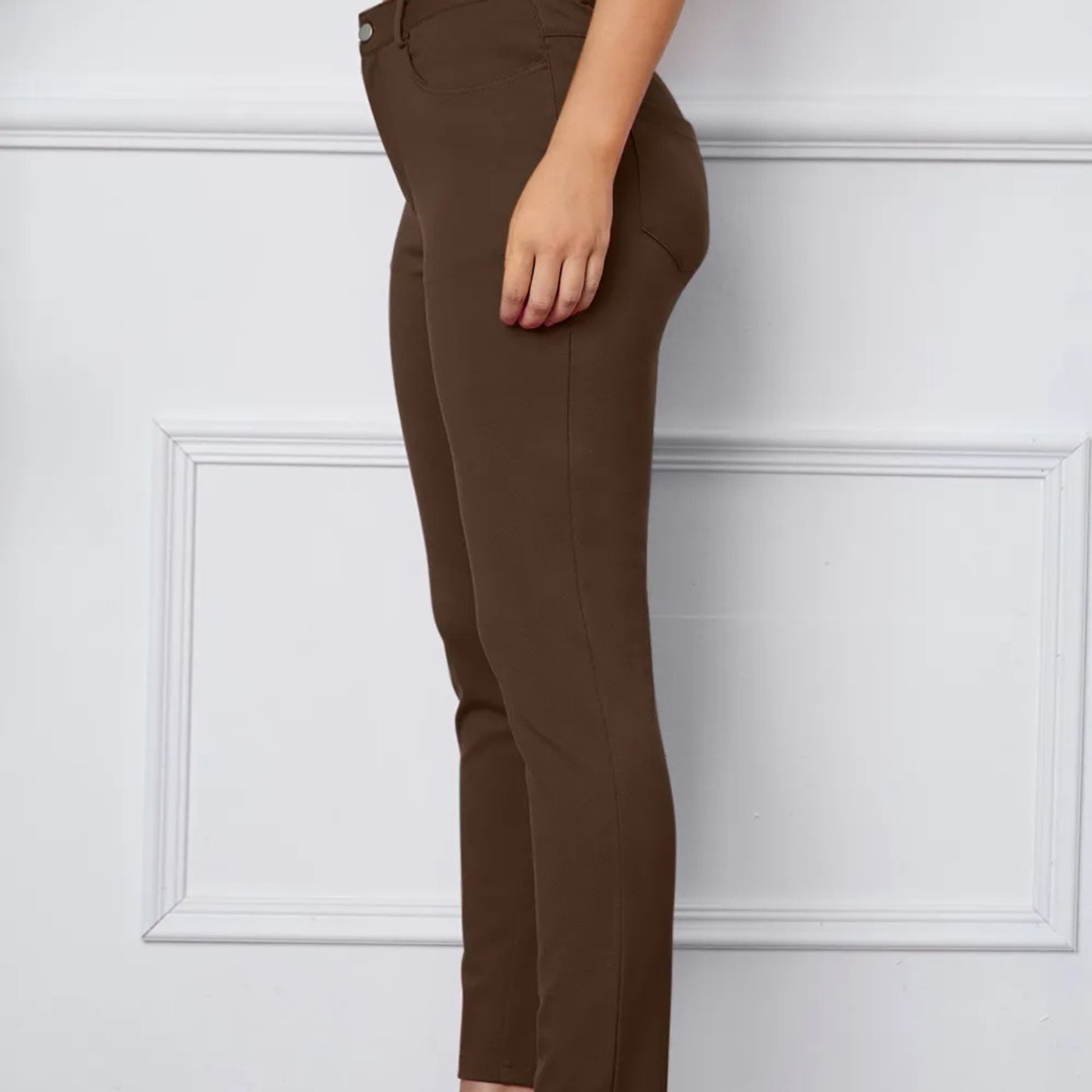 Brown pants worn by a person against a white paneled wall.