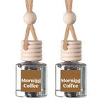 Two matching glass reed diffusers with clear bottles, beige wooden stoppers, and tan hanging cords, each labeled 'Morning Coffee' on a white background.