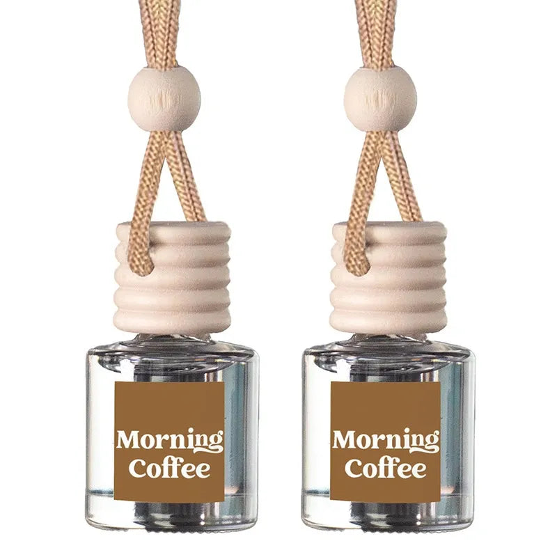 Two matching glass reed diffusers with clear bottles, beige wooden stoppers, and tan hanging cords, each labeled 'Morning Coffee' on a white background.