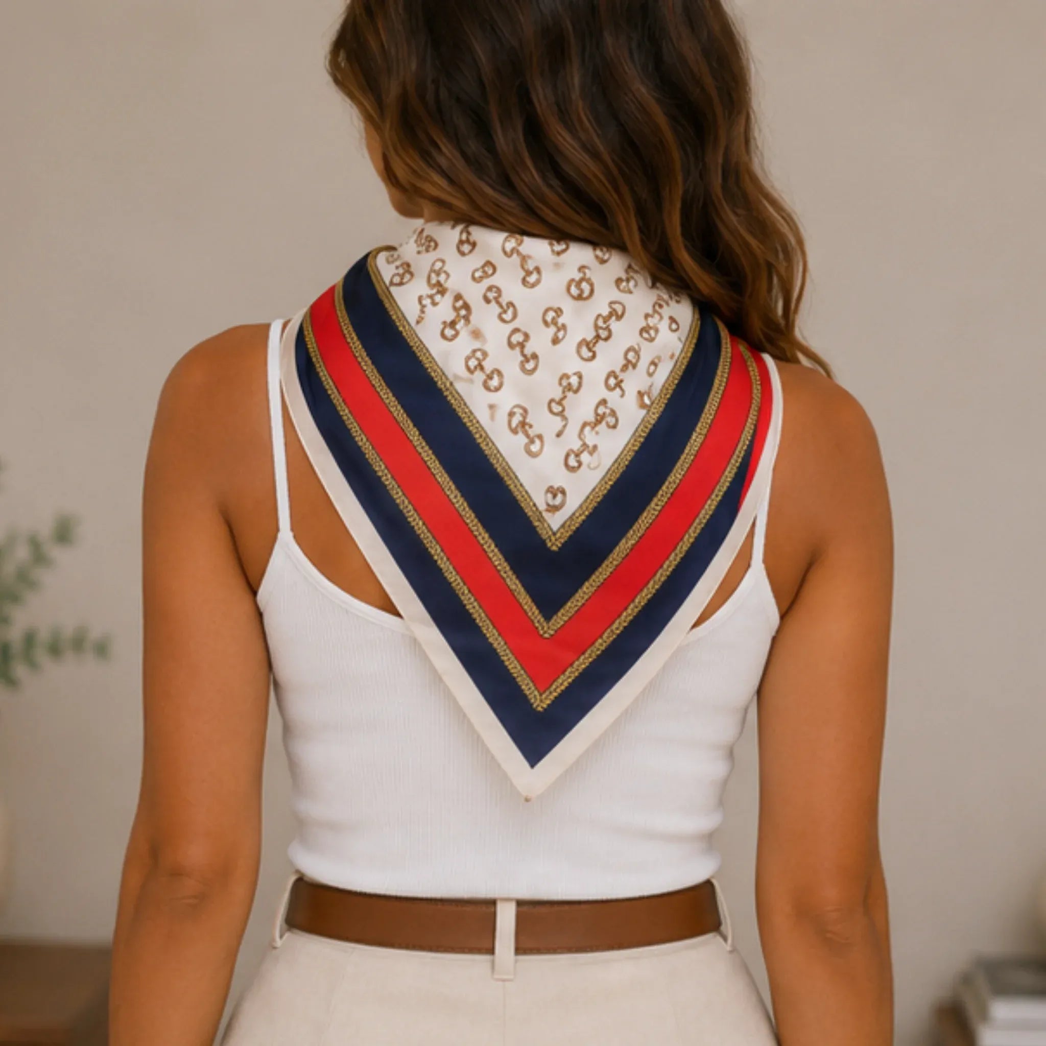 Back view of a woman wearing a navy multi print bandana scarf draped as a neck scarf.