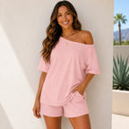Woman wearing the Off-Shoulder Lounge Top & Shorts 2-Piece Set in pink featuring a soft breathable fabric and pockets.