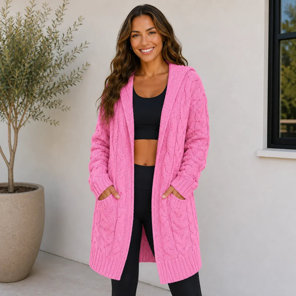Woman wearing a pink oversized cable knit open-front cardigan with hood and pockets