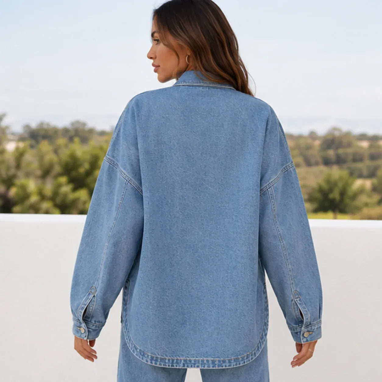 Back view of women's oversized blue denim shirt jacket showcasing the relaxed oversized fit and long sleeves.