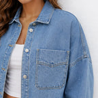 Close-up of the oversized blue denim shirt jacket highlighting the button-front closure, collar, and chest pocket stitching.