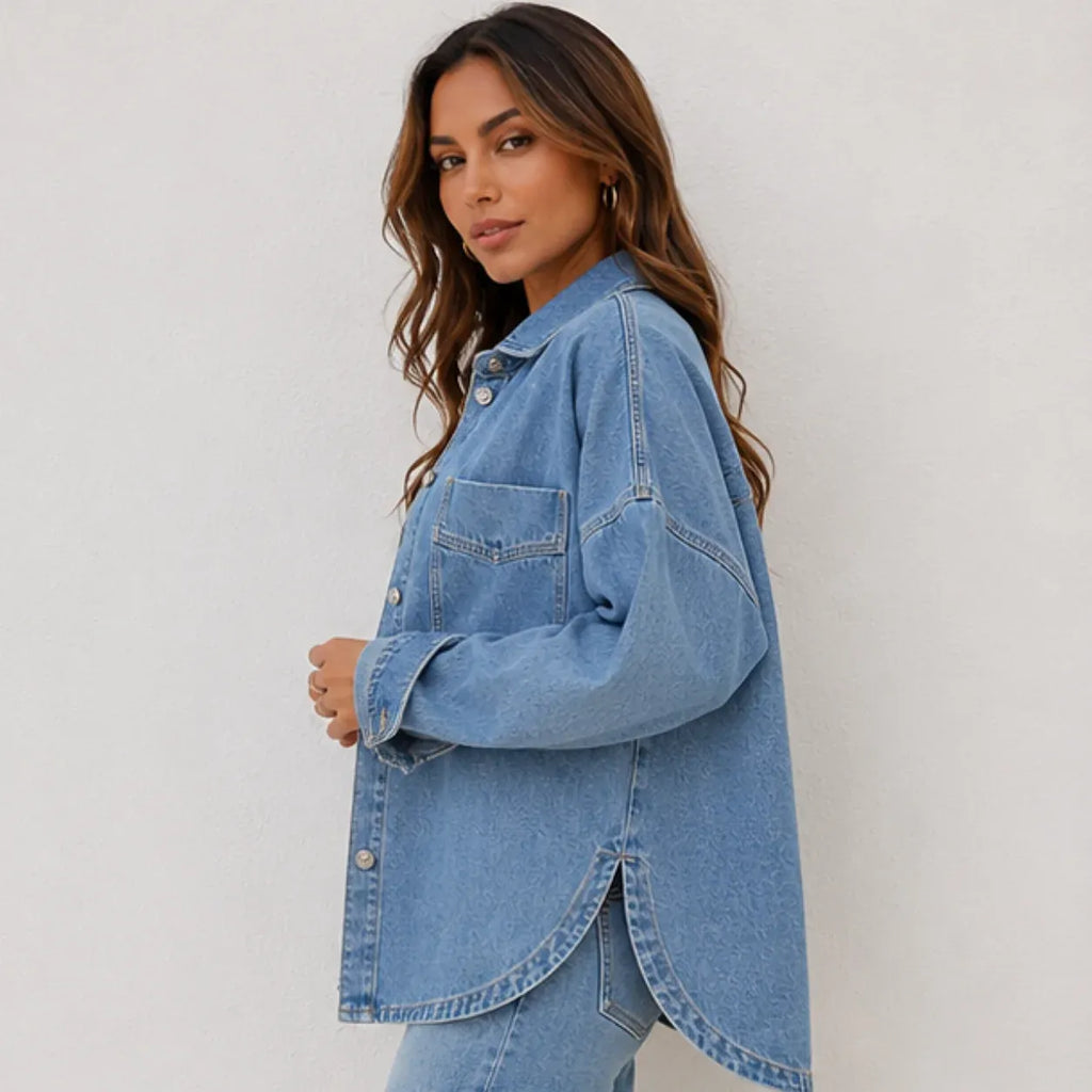 Side view of women's oversized blue denim shirt jacket with a relaxed silhouette, drop shoulders, and curved hem.